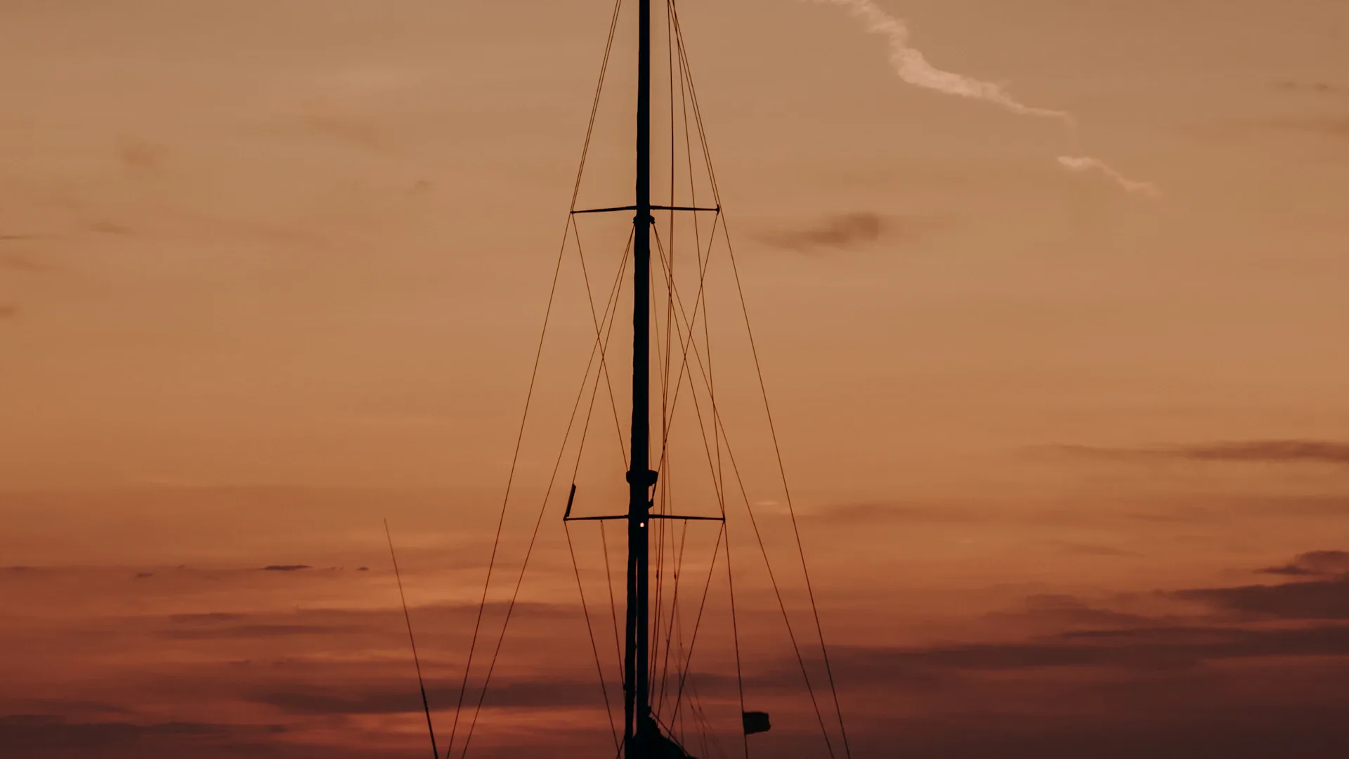 Sailing boat silhouetted on the water at sunset, an island on the horizon