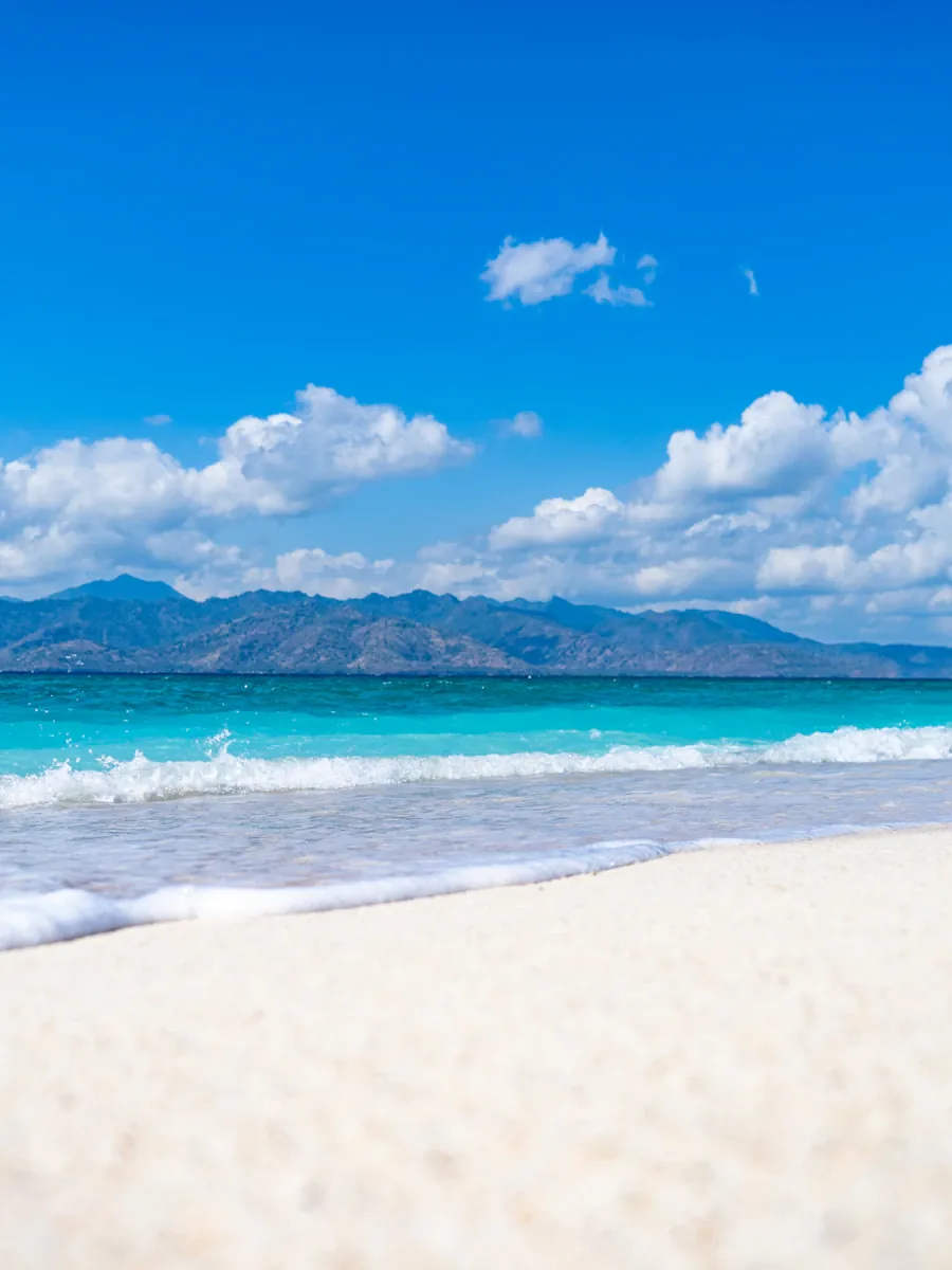 Wooden boat moored off a white-sand beach in clear water