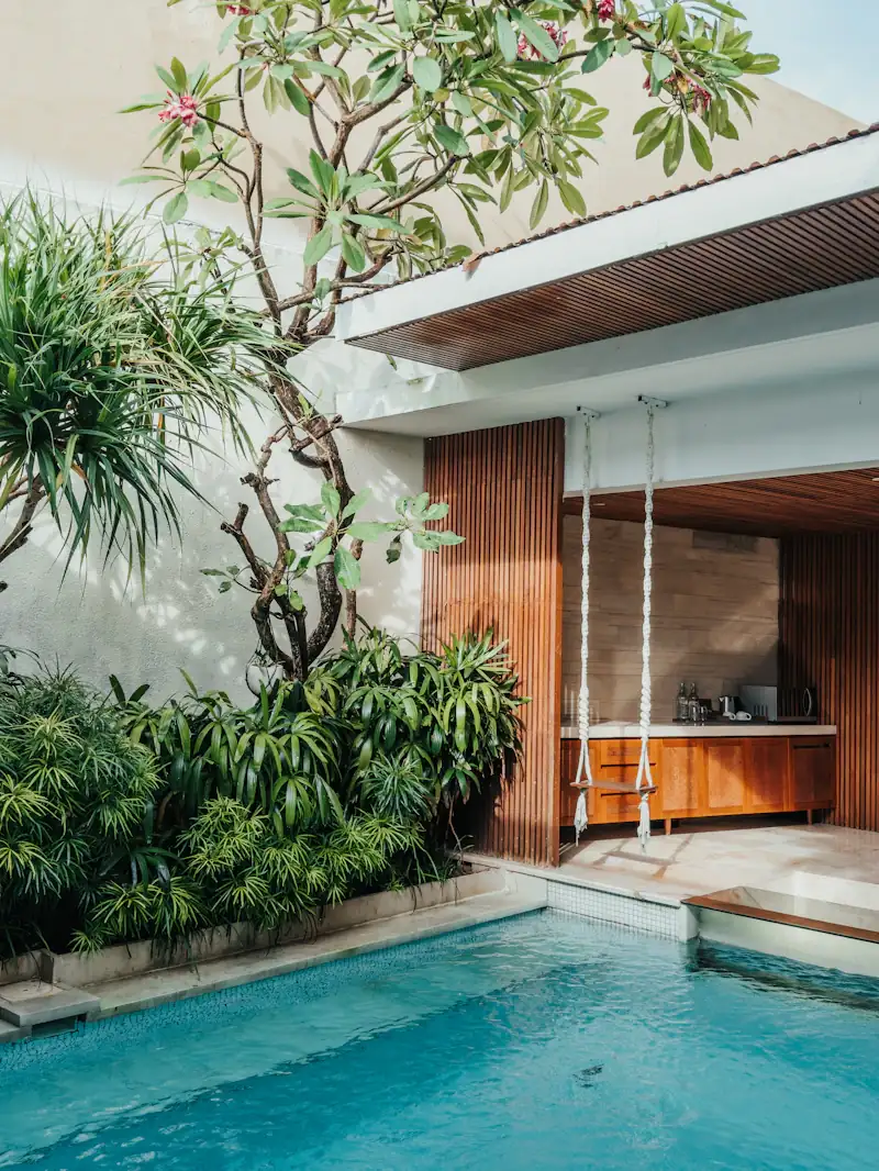 Private villa pool beside a timber pavilion and frangipani tree