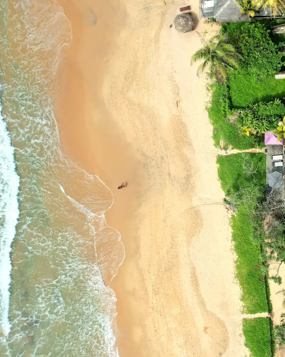 Top-down aerial of a villa and pool set right behind the sand