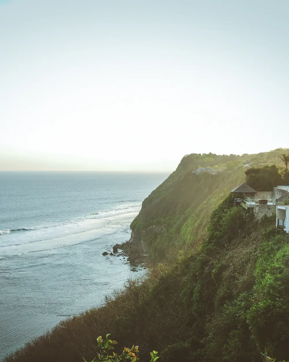 Villa built into a green headland above a surf coastline