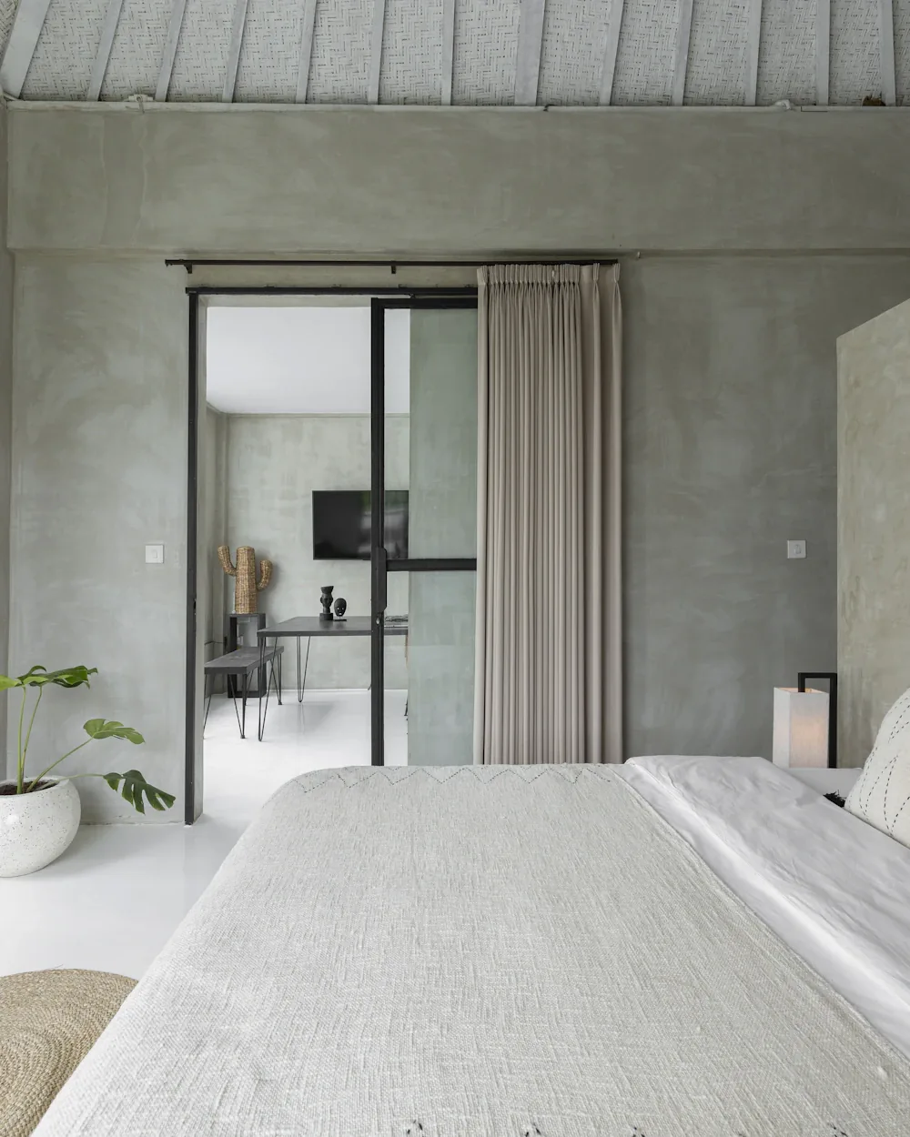 Calm villa bedroom with textured walls and sliding doors to the garden