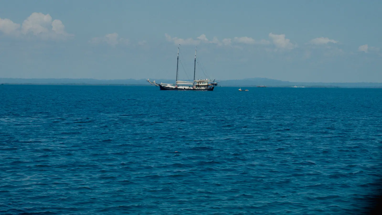 Two-masted phinisi schooner under way on open blue water
