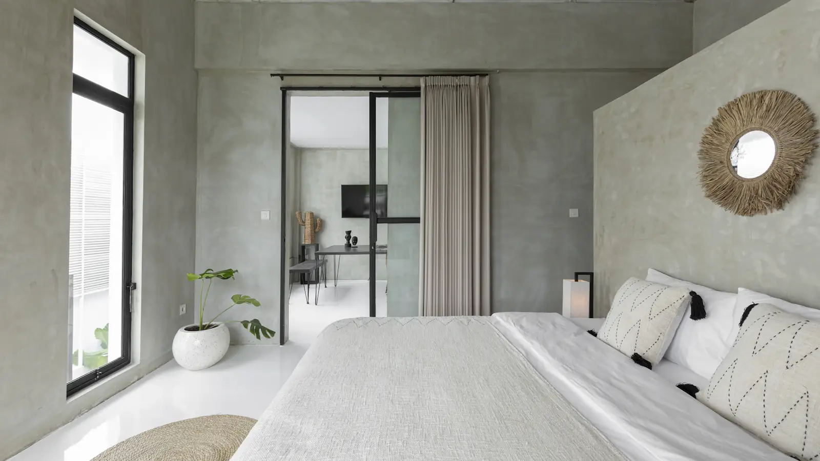 Calm villa bedroom with textured walls and sliding doors open to the garden