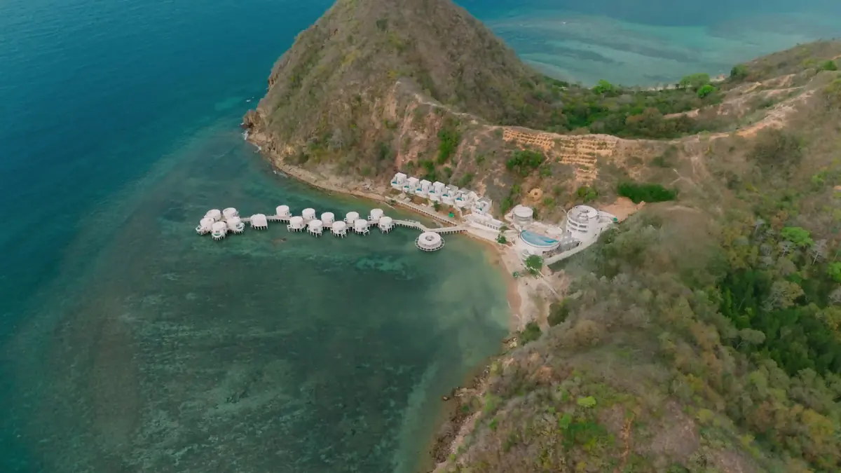 Aerial view of an overwater resort tucked into a green bay